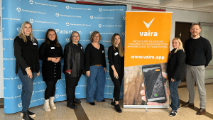 Vairas Geschäftsführer Max Erdmann gemeinsam mit 6 Mitarbeiterinnen der Agentur für Arbeit vor einem Banner der Agentur und Vaira für ein Gruppenfoto.