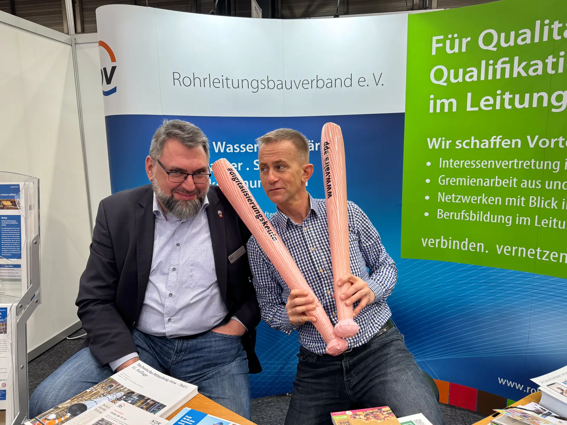 Christoph Kreutz und Helge Fuchs vom Rohrleitungsbauverband e.V. schwingen die Digitalisierungskeule von Vaira.