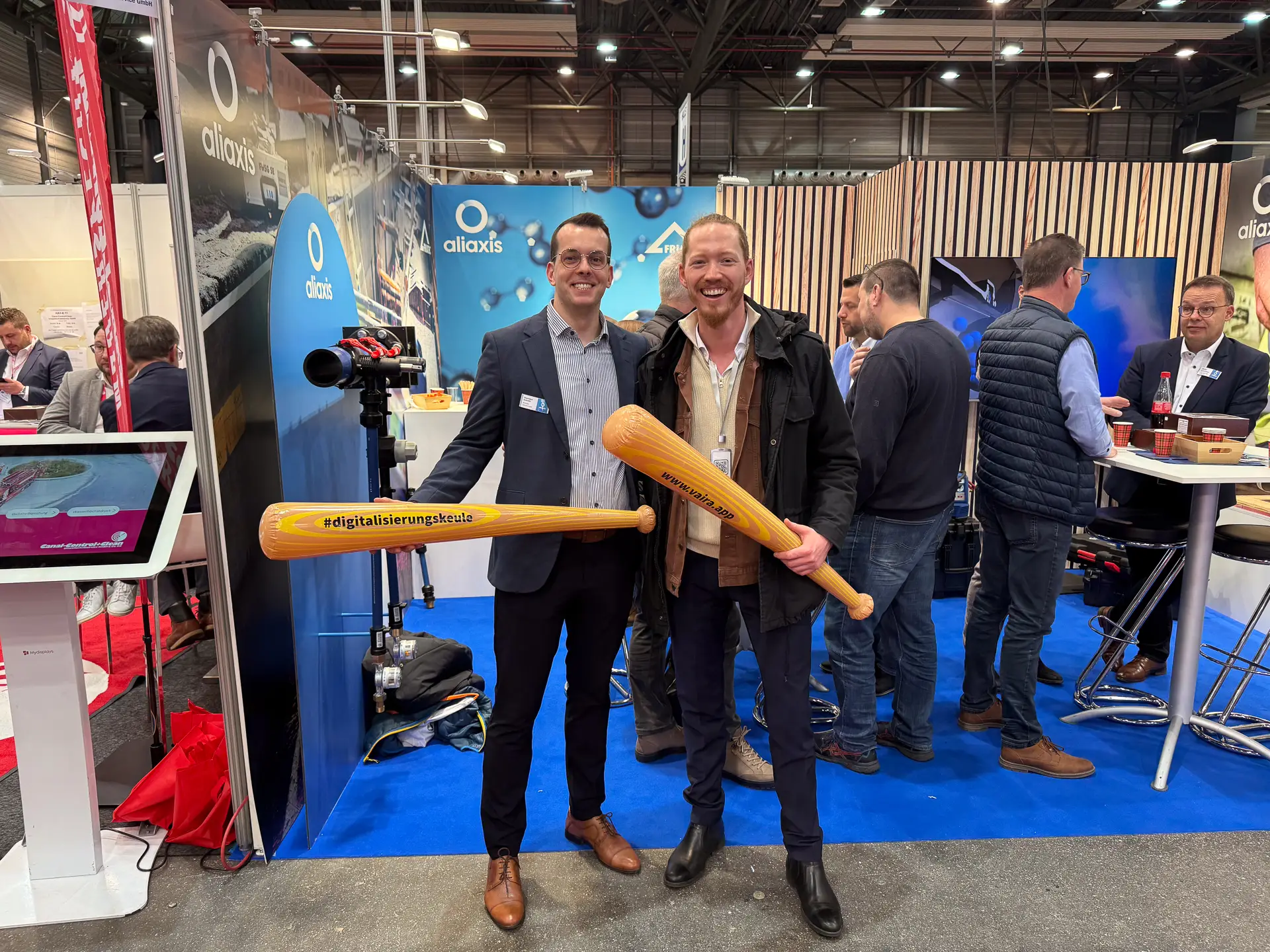 Gruppenfoto – (v.l.) Dominique Gallathe (Aliaxis) und Max Erdmann (Vaira) am Stand von Aliaxis auf der IRO 2025. Beide halten eine Digitalisierungskeule von Vaira in der Hand.