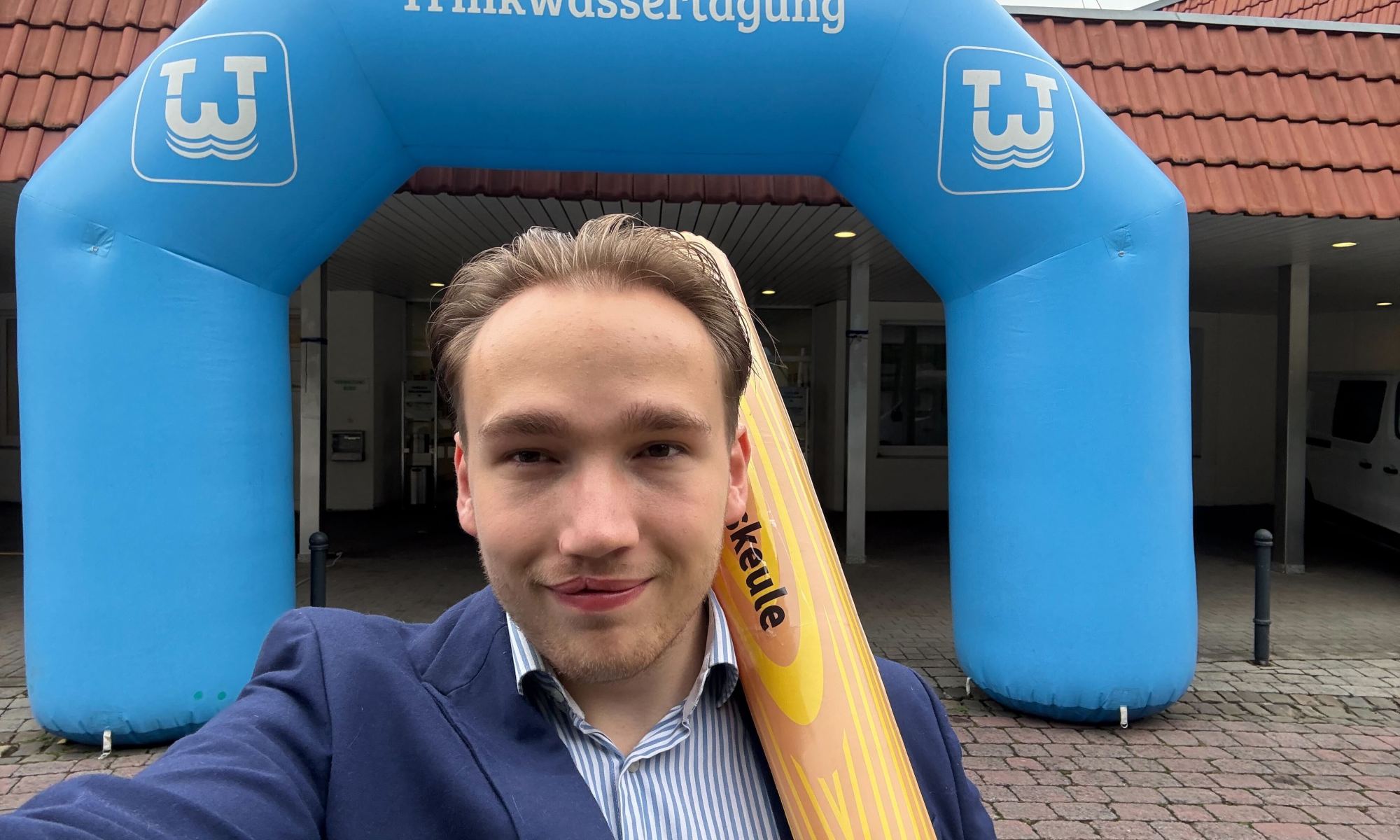 Lennard (Vaira) mit einer Digitalisierungskeule vor dem Eingang der 7. Westfälischen Trinkwassertagung 2025 in Paderborn.