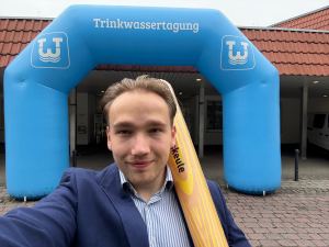 Lennard (Vaira) mit einer Digitalisierungskeule vor dem Eingang der 7. Westfälischen Trinkwassertagung 2025 in Paderborn.