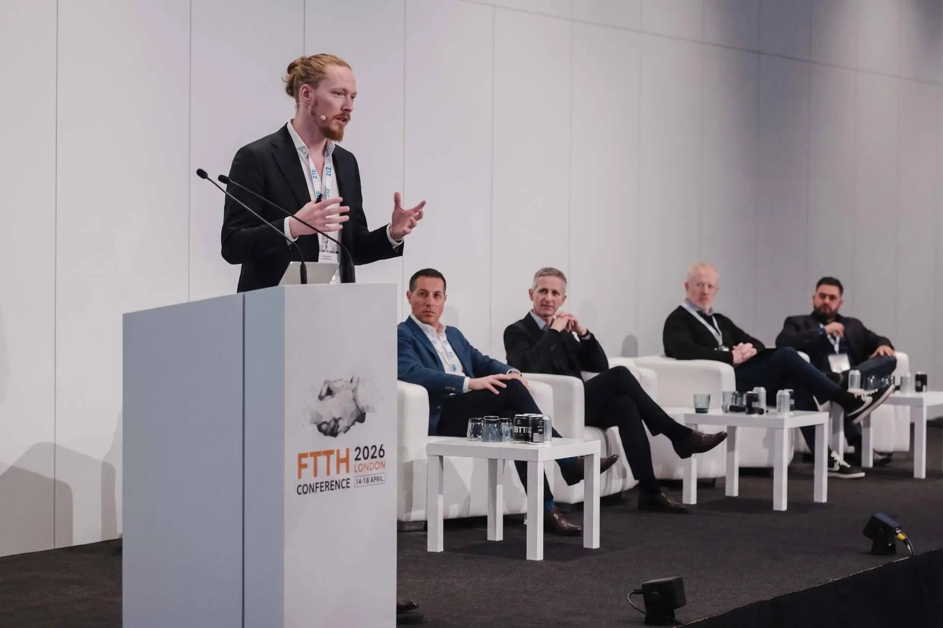 Max referiert auf der FTTH Conference 2026 in London über die digitale Baudokumentation – im Hintergrund sitzen weitere Redner, darunter auch Dario Conforti von Trimble